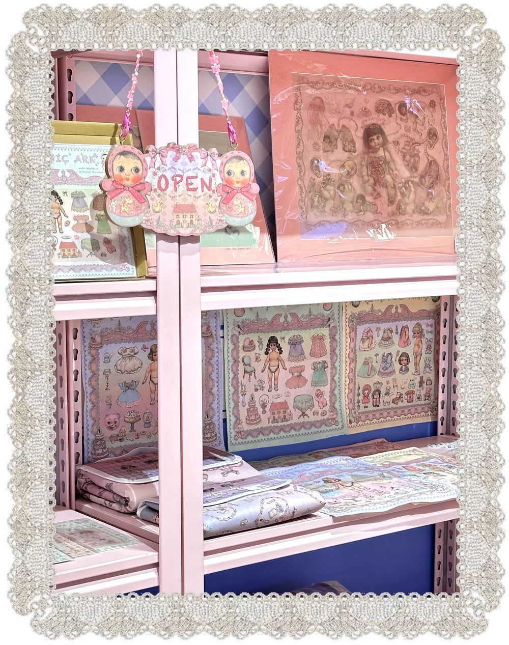 Shelf of RudeFish paper-doll prints under a hand-drawn OPEN sign